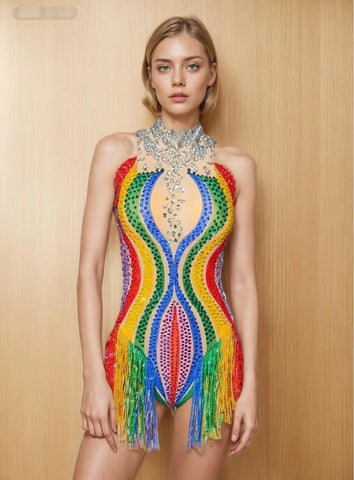 Model wearing a colorful, beaded dress with a wooden background