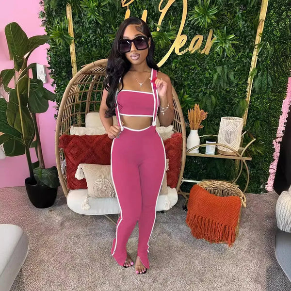 Woman in a pink outfit standing in a stylishly decorated room with plants and furniture.